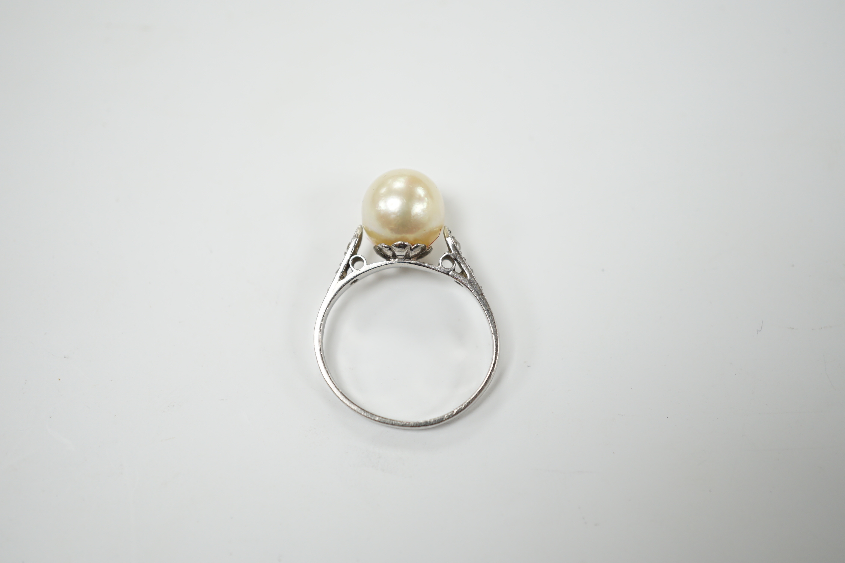 A white metal solitaire cultured pearl ring with diamond set shoulders, size J